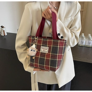 Close-up of red plaid canvas tote bag with woven handles and a cute alpaca keychain