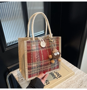 Close-up of linen tote bag featuring red plaid pattern, white button and plush charm