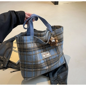 Détail du cabas en tweed à carreaux bleus avec breloque singe et poignées tissées