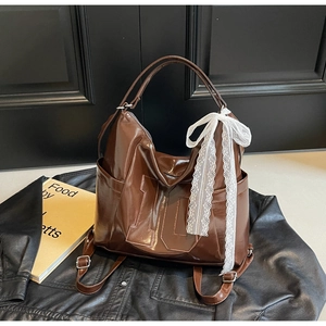 Gros plan d'un sac cabas marron foncé brillant avec nœud en dentelle et détails de couture