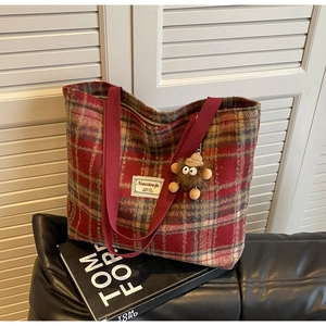 Détail du sac cabas en laine à carreaux rouges avec sangles et pendentif en peluche