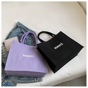 Dettaglio di borse tote in tela viola e nere con stampa merci in un ambiente casuale