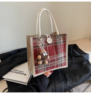Detail of checkered jute tote bag featuring a white button and large-eyed plush charm