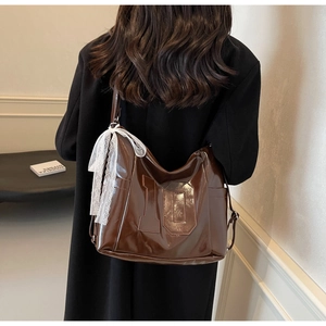 Détail d'un sac marron brillant avec broderie numéro dix et nœud en dentelle délicat