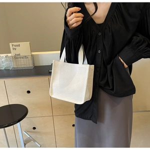 Close-up of a white tote bag featuring 3D embossed heart patterns with fabric handles