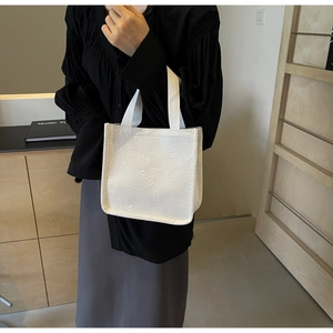 Detail of white mini tote bag featuring 3D heart embossed texture and woven handles