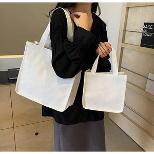 Detail showing two sizes of white heart quilted canvas tote bags with woven handles