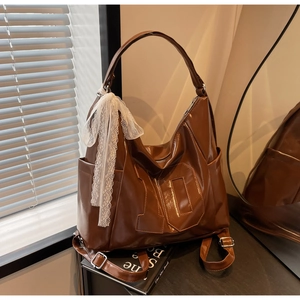 Vue détaillée du sac vintage marron en cuir avec écusson numéro et foulard en dentelle