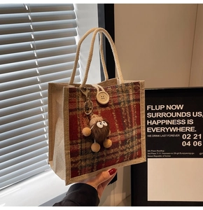 Detail of vintage plaid tote bag with large button closure and plush monster charm pendant