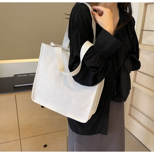 Detail of white tote bag with embossed heart patterns shown in a stylish lifestyle setting