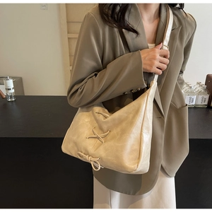 Détail du sac hobo crème avec cordon de serrage croisé et nœud décoratif élégant