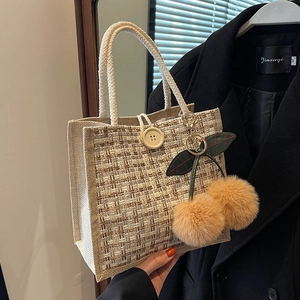 Linen woven bento handbag with wood button and plush cherry pendant on black coat