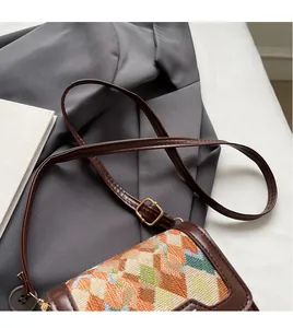 Detail of adjustable leather strap and tri-color checkered woven pattern on crossbody bag