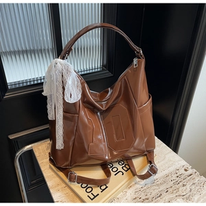 Détail du sac bandoulière en cuir marron rétro avec couture numéro 10 et nœud en dentelle