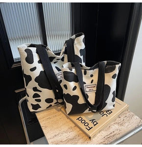 Gros plan de cabas en velours côtelé imprimé vache en deux tailles sur un décor minimaliste