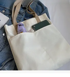 Close-up of off-white canvas tote bag with brown straps and large front pockets