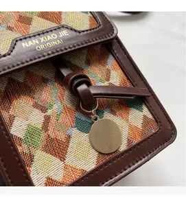 Close-up of woven geometric patterns and gold brand logo on the retro crossbody bag