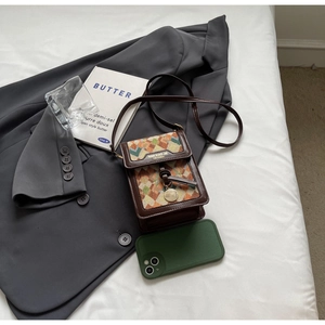 Flat lay of vintage crossbody bag with brown leather trim and geometric pattern on bed