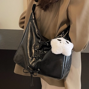 Grand sac cabas noir en cuir brillant avec lacets et breloque étoile porté par mannequin
