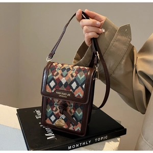 Close-up of a retro geometric woven crossbody bag with brown leather trim and metal pendant