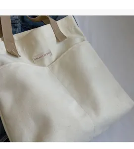 Detailed macro shot of durable off-white canvas bag featuring a front pocket and woven label