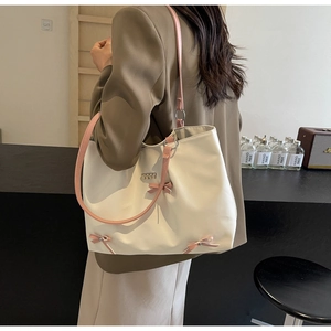 Detailed back view of a beige tote bag with pink bows and straps on a female model