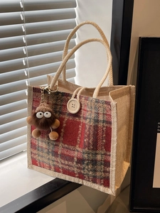 Linen tote bag with red plaid pattern, thick rope handles, and plush monster charm