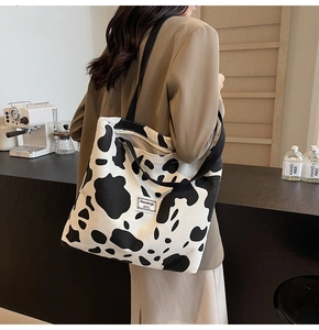 Détail d'un grand sac cabas à motif vache avec anses noires dans un café cosy
