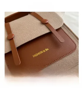 Detailed view of the textured felt material and brown leather flap on a vintage satchel
