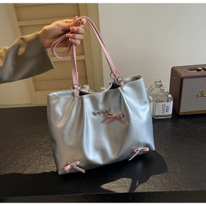 Close-up of silver metallic tote bag featuring pink bow details and heart buckle