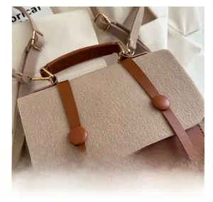 Detail of retro beige felt and brown leather crossbody bag with decorative buckles