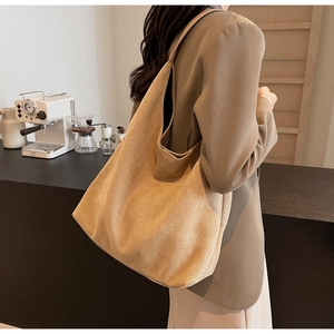 Close-up of a large caramel suede tote bag shown in a cozy cafe setting for fall style