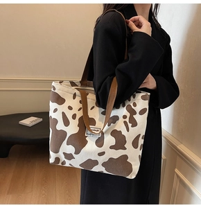 Gros plan d'un grand sac cabas en velours côtelé à motif vache porté à l'épaule