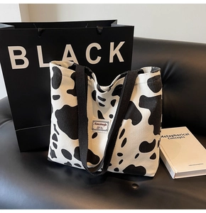 Détail du cabas en velours côtelé à motif vache avec anses noires et étiquette de marque