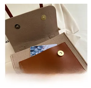 Detail of felt messenger bag featuring brown faux leather pocket and gold magnetic snap