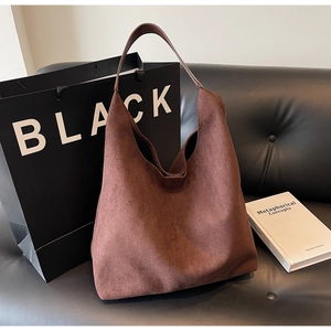 Brown suede tote bag displayed on black sofa with aesthetic lifestyle props