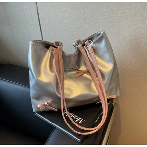 Detail of silver tote bag with pink bow accent and heart-shaped metal ornament