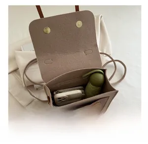 Internal storage view of tan felt crossbody bag showing phone, wallet and umbrella