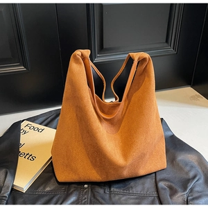 Detailed texture of caramel suede tote bag with leather trim on dark background