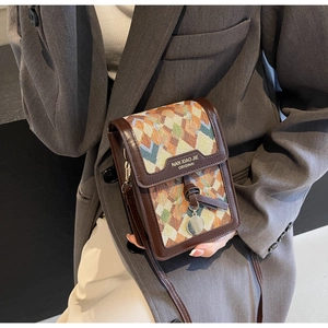 Detail of geometric jacquard fabric and brown leather trim on a crossbody phone bag