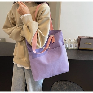 Detail of purple canvas tote bag with pink straps showing shoulder carry by a model