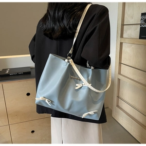 Detail of light blue tote bag with white bows and silver heart metal accents