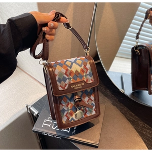 Detail of vintage crossbody bag featuring geometric woven fabric and metal pendant decoration