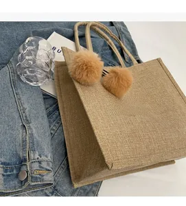Close-up of linen tote bag fabric with plush balls on a white table with lifestyle props