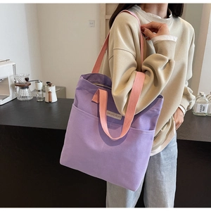 Detail of large canvas tote bag with purple body, pink straps and front pocket for A4 files