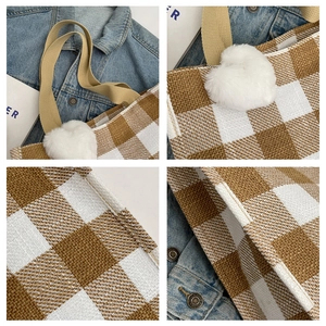 Detail of brown plaid canvas tote bag with plush heart charm and thick weave texture