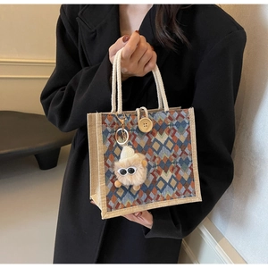 Close-up of geometric woven tote bag featuring cotton rope handles and plush charm