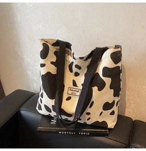 Détail de la texture en velours côtelé et des anses du sac cabas à motif vache noir et blanc