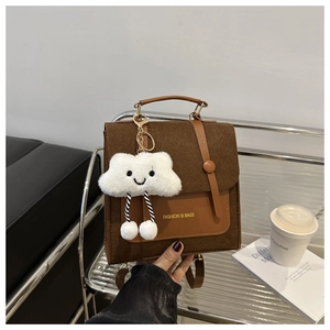 Detail of brown felt handbag with leather flap and cute plush cloud charm accessory