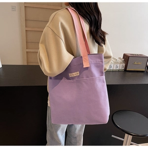 Detail view of purple canvas tote bag with pink wide strap and front pocket in retro setting